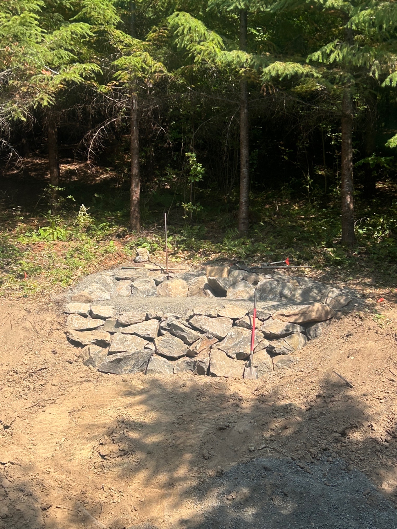 A stone-lined infiltration basin newly built into a forested hillside
